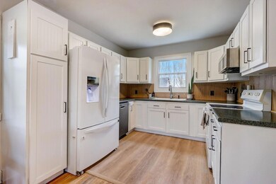 The kitchen is a standout feature with crisp white cabinetry and an adjoining informal dining space.