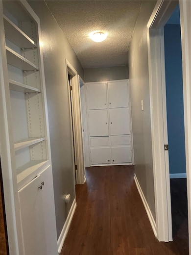 Hall with a textured ceiling and dark wood-style floors