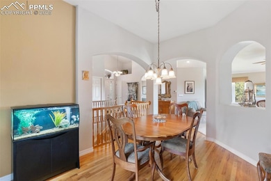 Dining room with light wood finished floors, arched walkways, high vaulted ceiling, and a chandelier