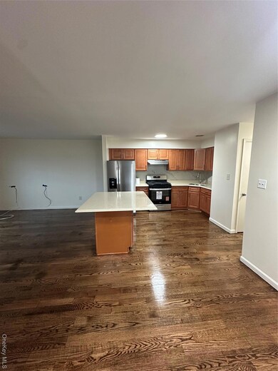 Kitchen featuring brown cabinetry, range, stainless steel fridge, and dark wood-style floors