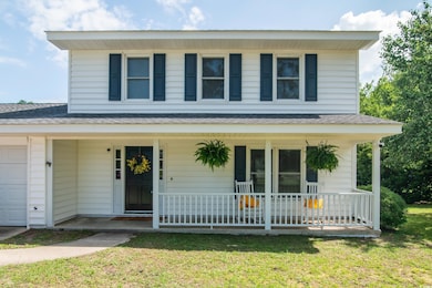 View of front of house with a porch, an attached garage, a shingled roof, and a front yard