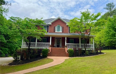 View of front of house with a porch, a front lawn, stairs, brick siding, and fence