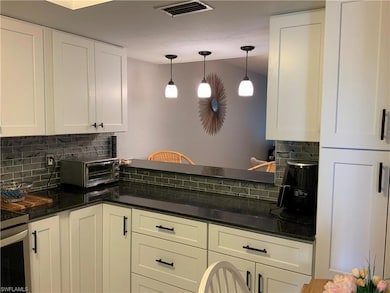 Kitchen with white cabinetry, backsplash, and pend