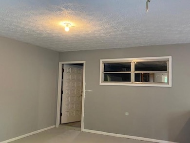 Unfurnished bedroom featuring a textured ceiling, baseboards, and carpet