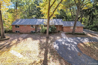 View of side of home with brick siding, a chimney, and view of scattered trees