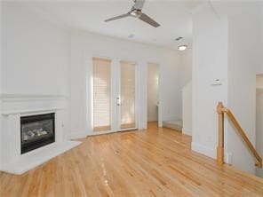 Unfurnished living room featuring a glass covered fireplace, light wood finished floors, and ceiling fan
