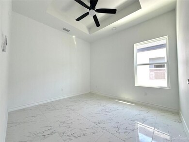 Unfurnished room with a tray ceiling, light marble finish flooring, and ceiling fan