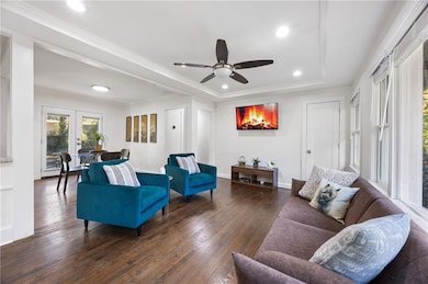 Living room with dark wood finished floors, a tray ceiling, recessed lighting, french doors, and a ceiling fan