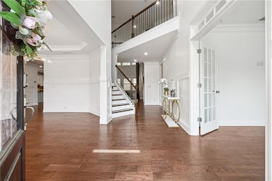 Entrance foyer with stairway, a high ceiling, crown molding, and wood finished floors