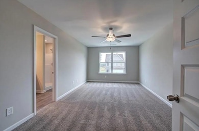 Carpeted spare room with ceiling fan and baseboards