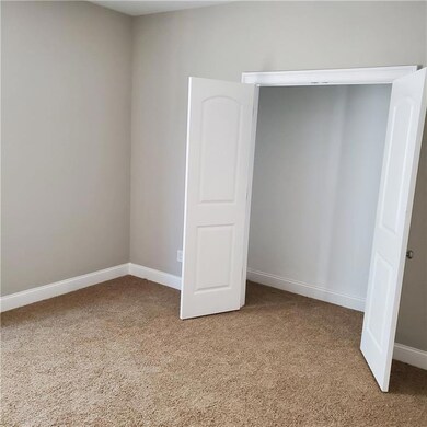 Unfurnished bedroom with light colored carpet and baseboards