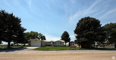 Ranch-style home featuring concrete driveway, a front yard, a garage, and a storage shed