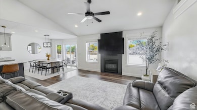Living room featuring recessed lighting, a fireplace, lofted ceiling, dark wood finished floors, and a ceiling fan