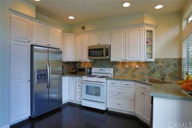 Kitchen showing white cabinets with pulls and gran