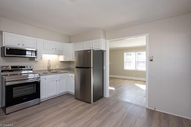 Eat In Kitchen: Features include new LVP flooring for easy cleaning, 2 windows for natural lighting and blinds for privacy, freshly painted bright cabinets, new granite counter tops and decorative backsplash, new SST appliances (microwave, stove and refrigerator), fresh new paint and decorative crown molding. The living room is to the right side. The refrigertor will convey with the home at closing.