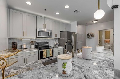 Kitchen with stainless steel appliances, light stone counters, decorative backsplash, hanging light fixtures, and recessed lighting