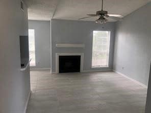 Unfurnished living room featuring a ceiling fan and a fireplace