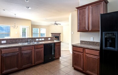 Kitchen featuring black appliances, a fireplace, dark countertops, a chandelier, and ceiling fan