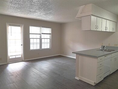 Kitchen with baseboards, a sink, and a textured c
