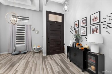 Foyer entrance with a high ceiling, a chandelier, and light wood-style floors