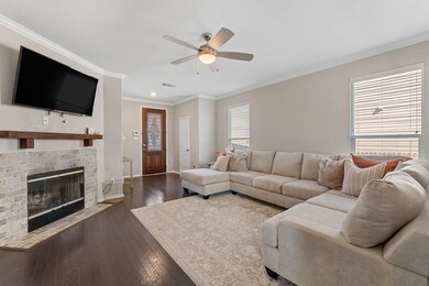 Living area featuring crown molding, dark wood-style floors, a fireplace, and ceiling fan