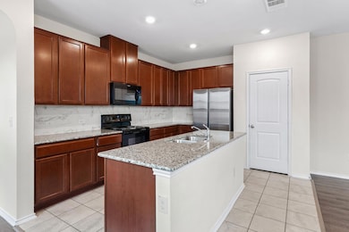 Kitchen with black appliances, light tile pattern