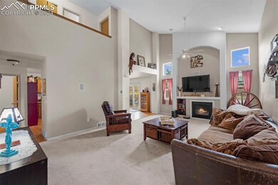 Carpeted living room with ceiling fan and high vau