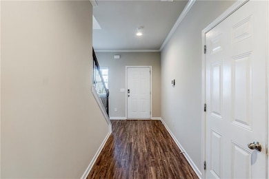 Doorway featuring ornamental molding, dark wood-type flooring, baseboards, and stairs