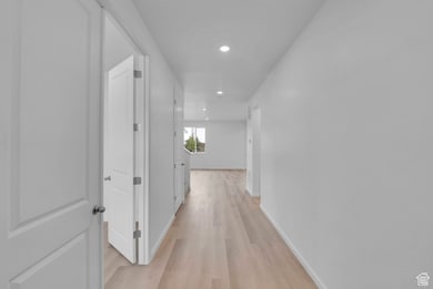 Hall with light wood-style flooring, recessed lighting, and baseboards