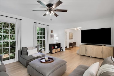 Living area with light wood-style flooring, ceiling fan, and a chandelier