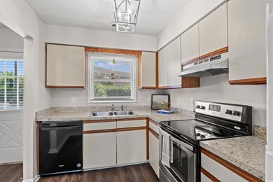 Kitchen with white cabinets, dishwasher, dark wood