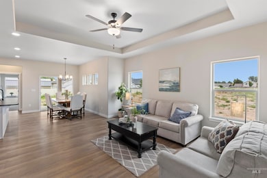Living room with a tray ceiling, a ceiling fan, wood finished floors, plenty of natural light, and recessed lighting
