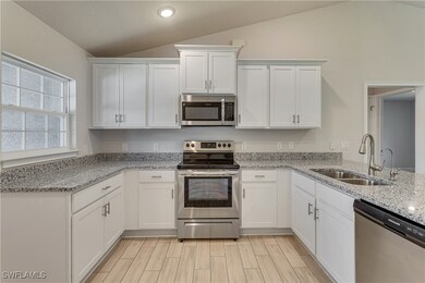 Kitchen with white cabinetry, appliances with stai