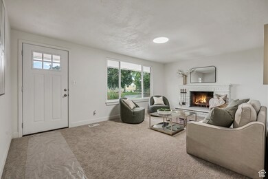 Carpeted living area featuring a fireplace and baseboards