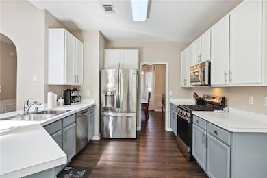 Kitchen with white cabinets, stainless steel appliances, dark hardwood / wood-style floors, sink, and gray cabinets