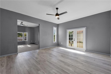 Dining room with a textured wall, ceiling fan, french doors, healthy amount of natural light, and light wood-style floors