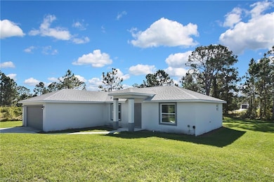 View of front of home with a front yard, roof with shingles, an attached garage, and stucco siding