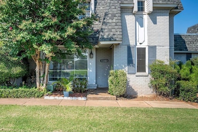 View of exterior entry with brick siding, a yard, and a shingled roof