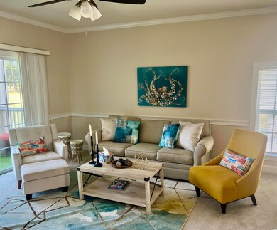 Carpeted living room featuring ceiling fan and orn