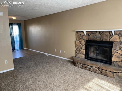 living room with carpet floors, and a stone fireplace