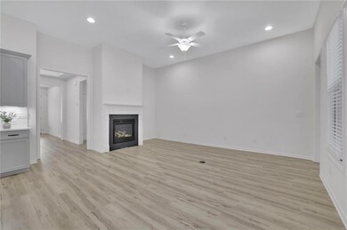 Unfurnished living room featuring a ceiling fan, light wood-type flooring, a glass covered fireplace, and recessed lighting