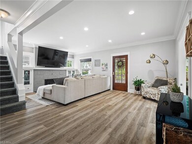 Living room with crown molding, a fireplace, and light hardwood flooring