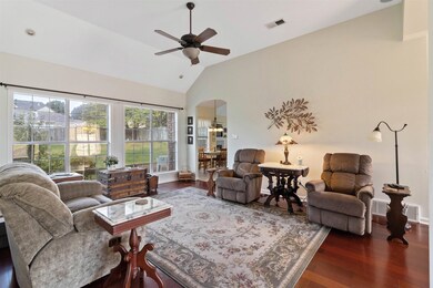 Living area featuring dark wood-style floors, a ceiling fan, arched walkways, and high vaulted ceiling