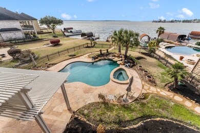 Before we go inside, we’d like to give you a sneak peek at the incredible backyard!  Everything you need for entertaining and vacation-style living is here!  You have a deep covered porch with additional slatted roof covered patio.  Your pool/spa features a large rock waterfall highlighted by mature tropical trees. A flagstone path leads down to the water and the boat slip.