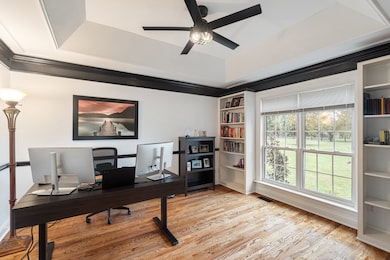 Office with built in bookshelves, tray ceiling and crown molding