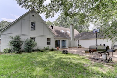 Rear view of house featuring brick siding, a patio area, a yard, a chimney, and board and batten siding