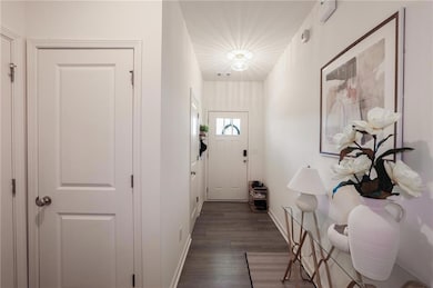 Doorway to outside with dark wood-type flooring and baseboards