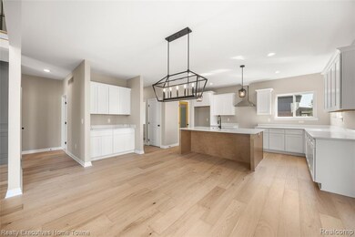 Kitchen with light wood-style flooring, light stone countertops, recessed lighting, hanging light fixtures, and white cabinetry
