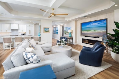 Living room with ceiling fan, light wood-style flooring, coffered ceiling, a large fireplace, and recessed lighting