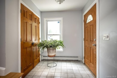 Entryway with light tile patterned floors and baseboard heating